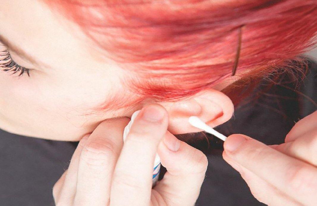אישה מנקה את האוזן שלה עם מקל צמר גפן