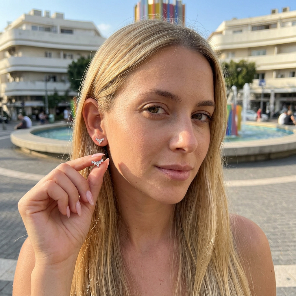 דוגמנית עם שיער בלונד מחזיקה עגיל בעיצוב כתר ואחד על האוזן שלה עגיל כסף 925